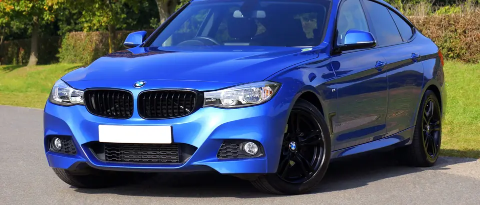 Blue sports sedan parked under fall trees