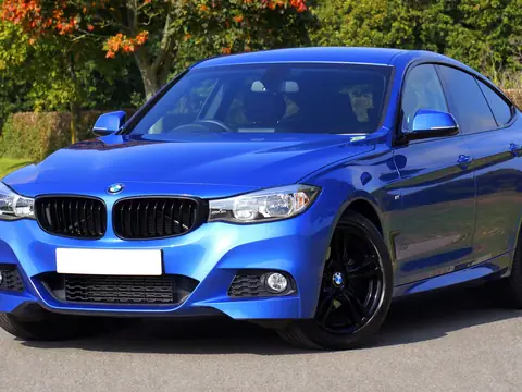 Blue sports sedan parked under fall trees