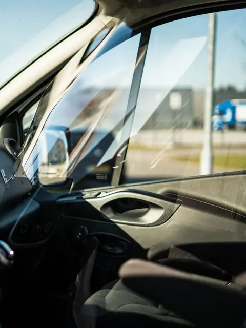 The door glass, A-pillar and mirror of a van, seen from the driver seat