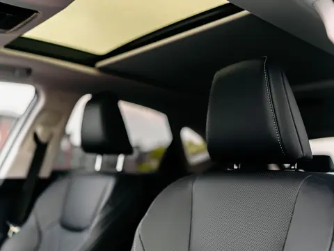 Black leather front seats of a car under an open glass panel overhead